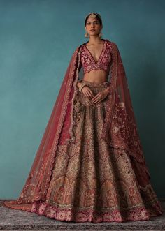 a woman in a red and gold lehenga, with her hands on her hips