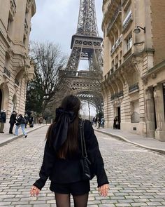 a woman standing in front of the eiffel tower with her back to the camera