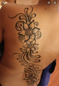 the back of a woman's shoulder with flowers on it and swirls in the middle