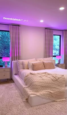 a large white bed sitting in the middle of a bedroom next to a purple light