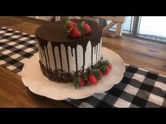 a chocolate cake with strawberries on top is sitting on a table next to a black and white checkered placemat