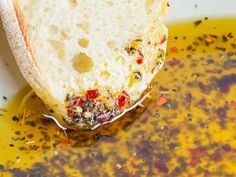 a piece of bread sitting on top of a bowl filled with olive oil and mustard