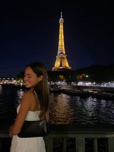 a woman standing in front of the eiffel tower at night