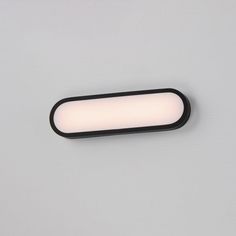 a close up of a light on a wall with a white surface and black trim