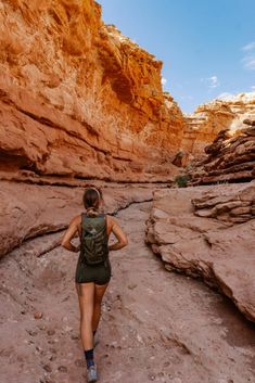 a woman hiking through the desert with her back to the camera