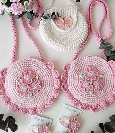 pink crocheted purses and matching accessories are displayed on a white table top