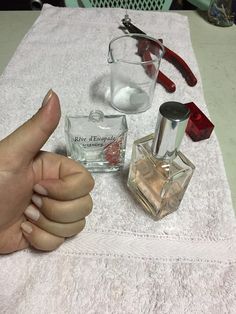 a person is giving the thumbs up next to some perfume bottles and eyeglasses