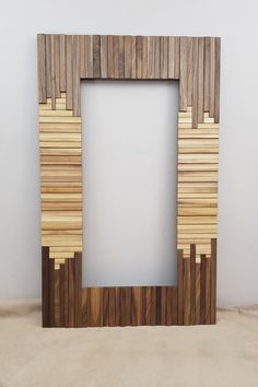 a wooden frame sitting on top of a floor next to a white wall with wood planks