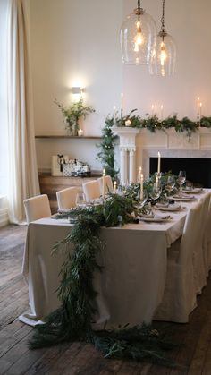 the table is set with candles, greenery and white linens for an elegant look