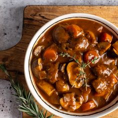 vegan irish guinness stew in a white bowl with rosemary garnish on top