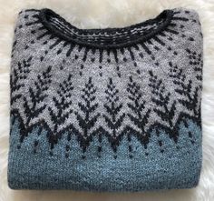 a blue and gray sweater sitting on top of a white furnishing covered floor