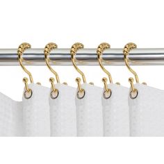 four curtain hooks hanging on the side of a white curtain with gold colored metal rods