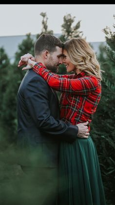 a man and woman hugging each other in front of christmas trees at an outdoor tree farm