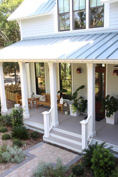 a white house with some plants on the front porch