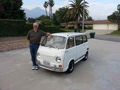 a man standing next to a small white car