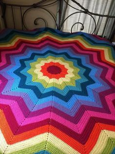 a multicolored crocheted blanket on top of a bed