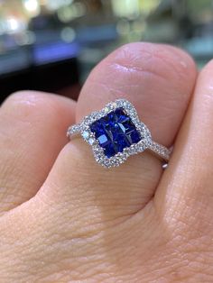 a woman's hand holding a blue and white diamond ring