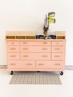 a pink dresser sitting on top of a rug next to a white wall with a sewing machine