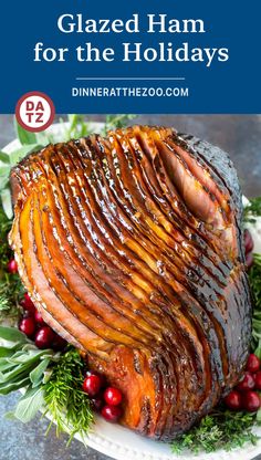 glazed ham for the holidays on a plate with cranberries and greenery around it