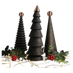 three wooden christmas trees on display with holly and berries around the base, set against a white background