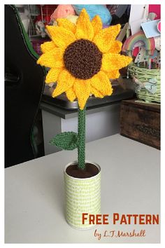 a crocheted sunflower sitting on top of a table next to a cup