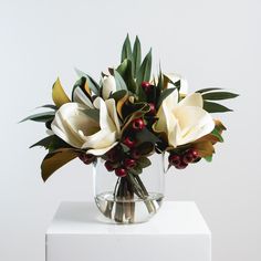 a vase filled with white flowers and greenery