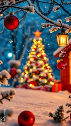 a christmas tree with lights and ornaments in the snow next to a small red house