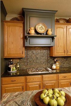 a bowl of pears sits on the counter in this kitchen with wooden cabinets and granite counter tops