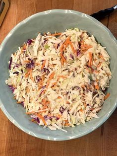 a bowl filled with coleslaw and carrots on top of a wooden table