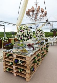 a table with flowers on it under a chandelier in the middle of an outdoor area