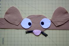 an animal mask made out of brown paper with eyes and nose cut out to look like a mouse