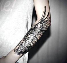 a person with a tattoo on their arm and an angel wing tattooed on the arm