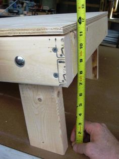 a person measuring the height of a wooden bench with a tape measure ruler on it