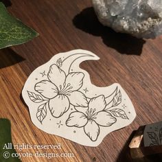 a wooden cutting board with flowers and leaves on it next to a knife sharpener