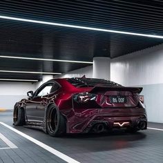 a red sports car is parked in a parking garage with its hood up and lights on