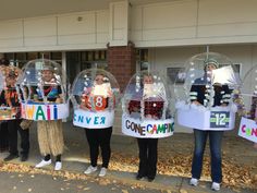 four people standing in front of a building with fake snow globes on their heads