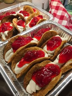 two pans filled with sandwiches covered in jelly and whipped cream sitting on top of a counter