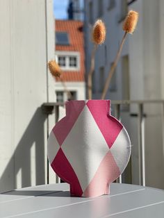 a pink and white vase sitting on top of a table next to a planter