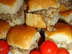 several hamburgers with meat, cheese and tomatoes on a white plate next to some red cherries