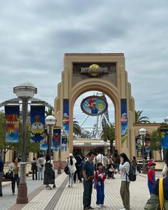 many people are standing in front of the entrance to an amusement park