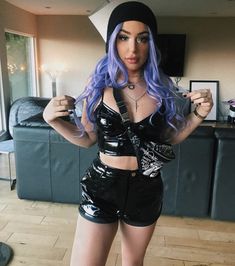 a woman with blue hair and black shorts posing for the camera in her living room