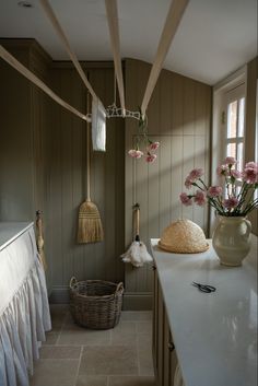 a kitchen counter with flowers in a vase on it and hanging utensils from the ceiling