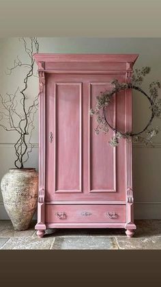 a pink armoire sitting next to a vase