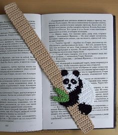 a crocheted bookmark with a panda bear on it sitting on top of an open book