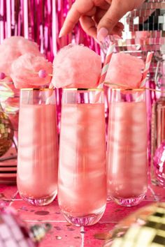 three glasses filled with pink liquid on top of a table next to confetti