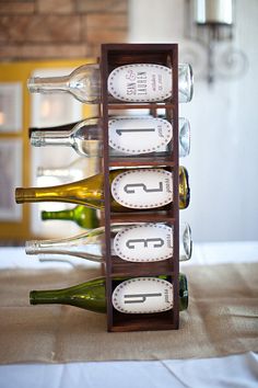 wine bottles are stacked on top of each other in front of a table with white linens