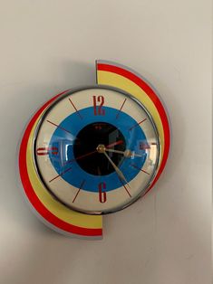 a clock that is on the wall with red, yellow and blue circles around it