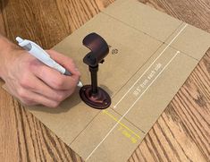 a person writing on a piece of brown paper with a white pen in their hand