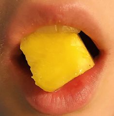 a close up of a child's mouth with a piece of cheese on it