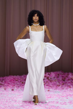 a model walks down the runway in a white gown